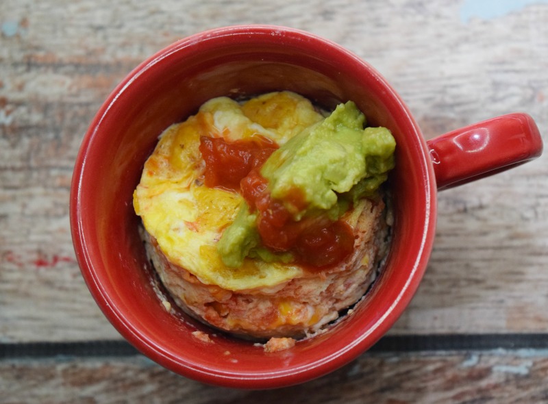 Microwave Migas in a mug topped with salsa and guacamole.