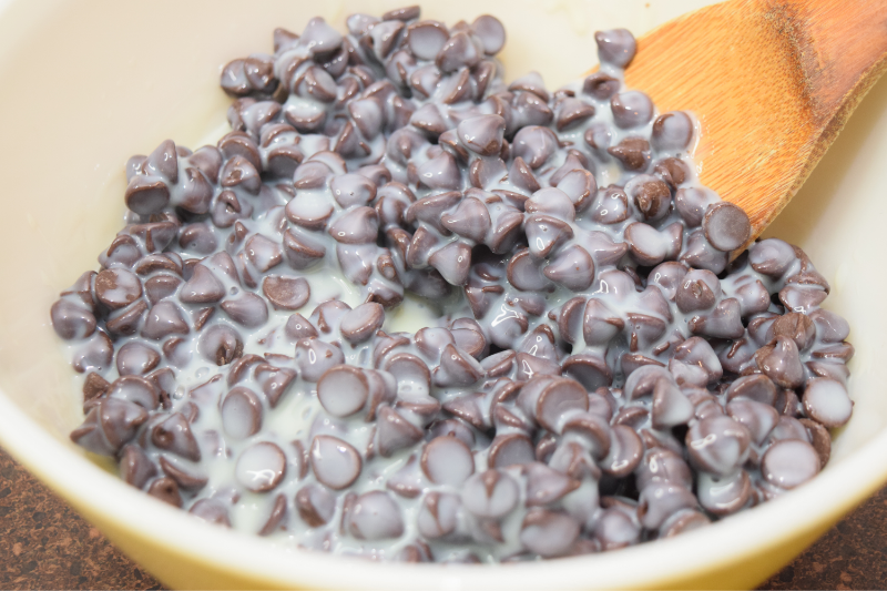 A bowl of chocolate chips covered in sweetened condensed milk.