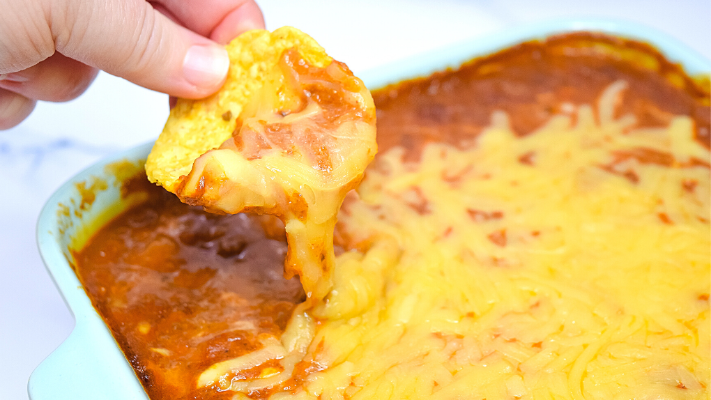 A tortilla chip being dipped into the Too Easy Tamale Dip