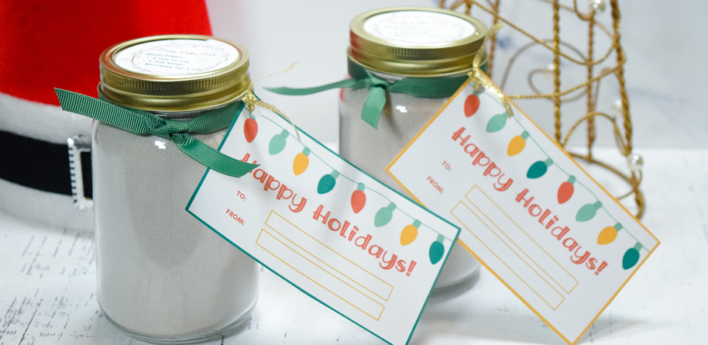 Two jars of mug cake mix with stickers and holiday tags ready for gifting