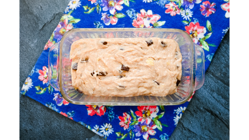 Chocolate Chip Banana Bread in a glass loaf pan on a blue floral towel. 