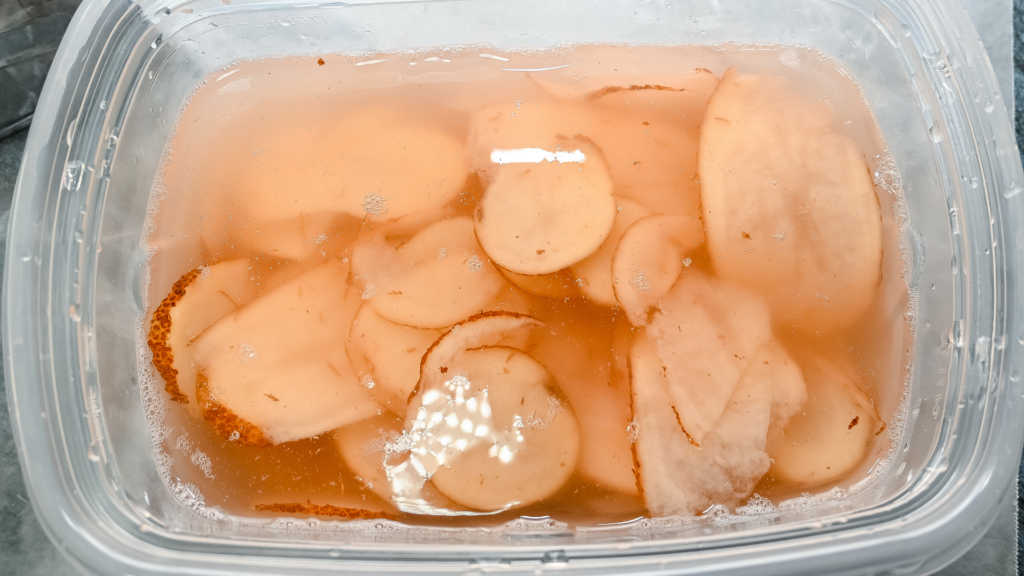 A close up of the potato slices in the ice water. 