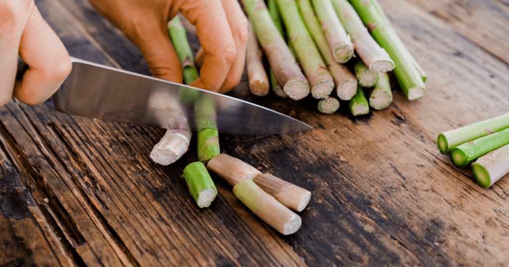 Cutting the woody stems from fresh asparagus before cooking.