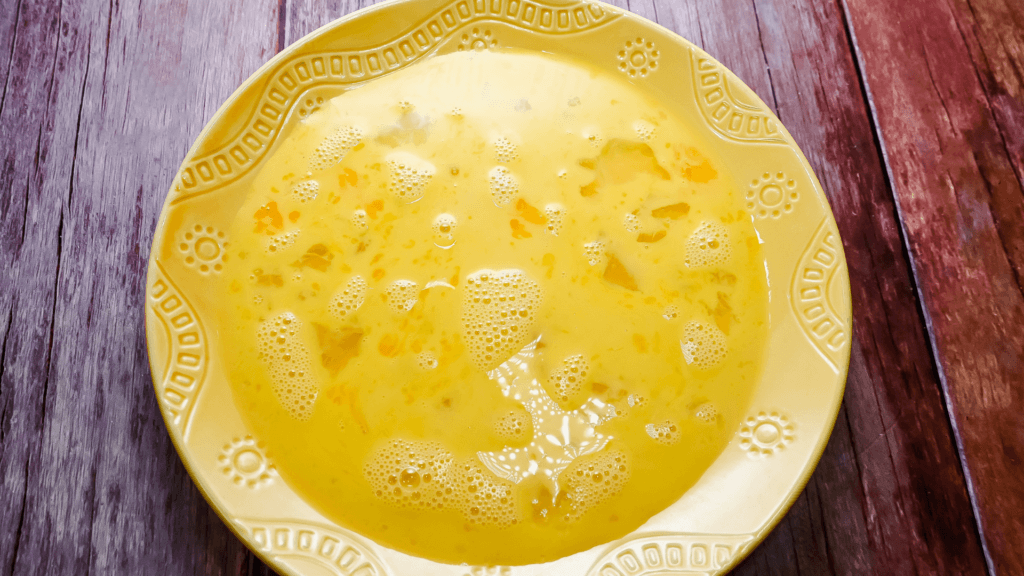 raw eggs and milk mixture on a yellow plate