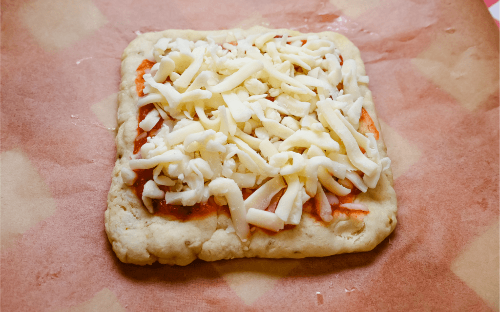 The pizza crust with cheese over the sauce. 