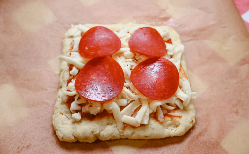 The pizza crust with toppings on the cheese and sauce. 