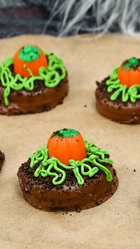 Close up of three chocolate covered Pumpkin Patch OREO cookies on brown parchment paper. 