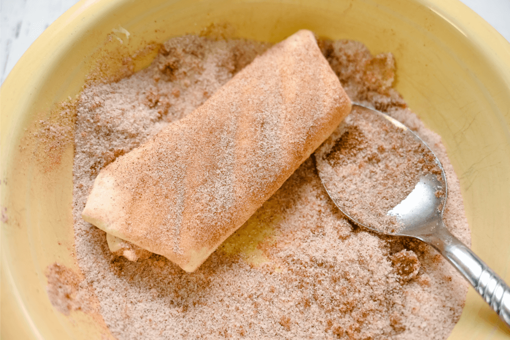Tossing the cheesecake chimichanga in the cinnamon and sugar. 