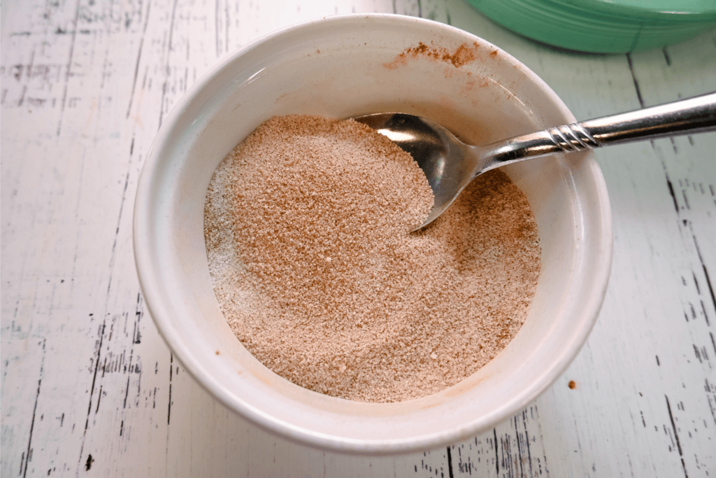 The cinnamon and sugar mixture for dipping in a white bowl. 