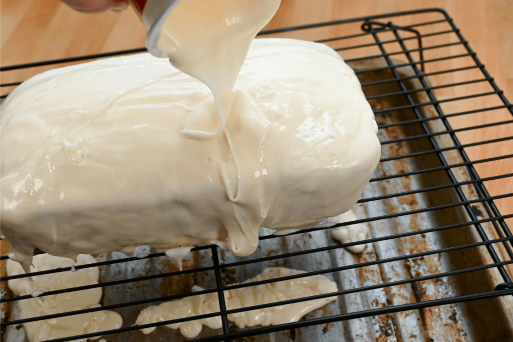 Pouring microwave frosting over the sides of cake