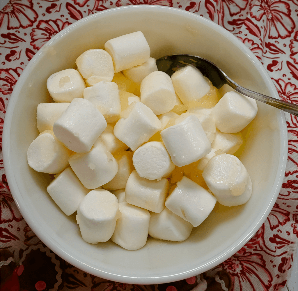Marshmallows mixed with the butter sugar mixture in a white glass bowl
