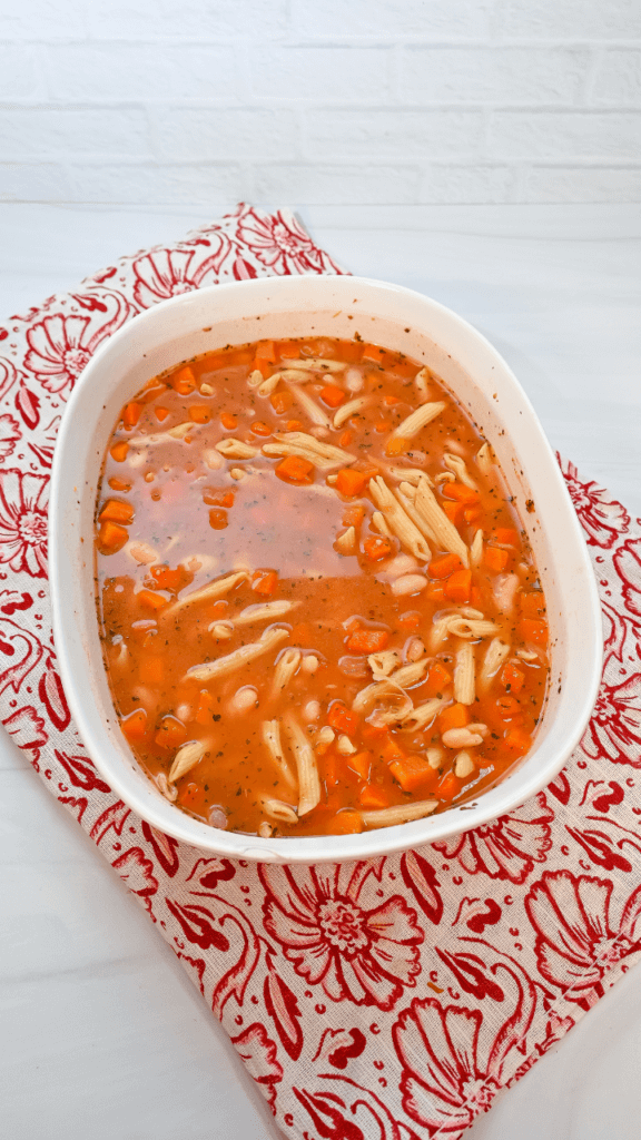 All the ingredients of the pasta fagioli mixed together in a microwave-safe white glass container