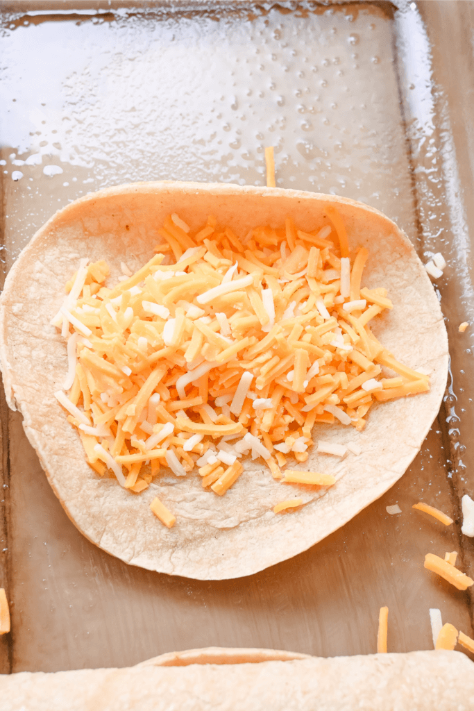 A close up of a tortilla filled with shredded cheese. 