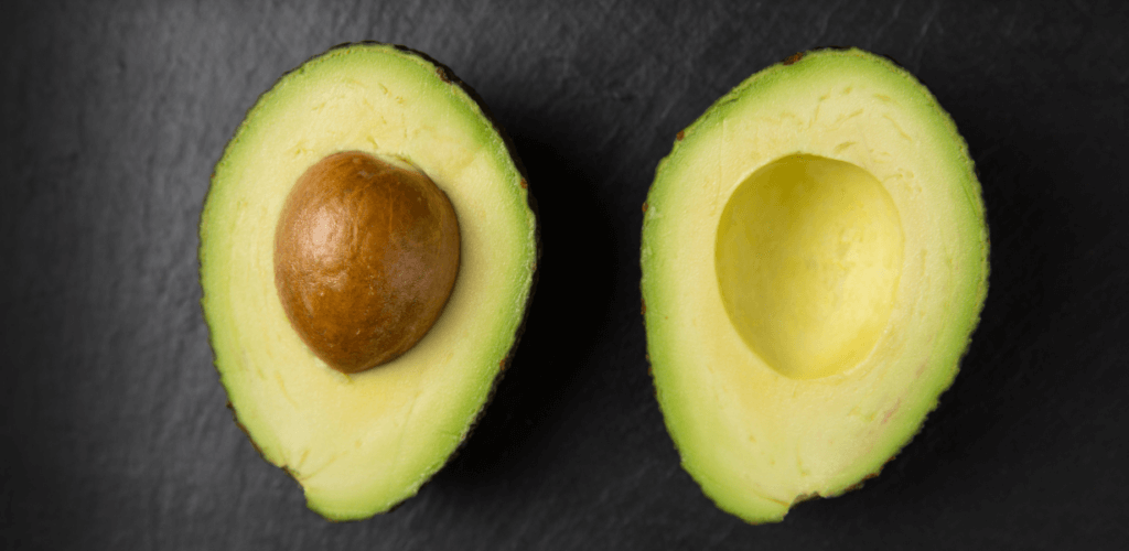 Two halves of an avocado on a black service