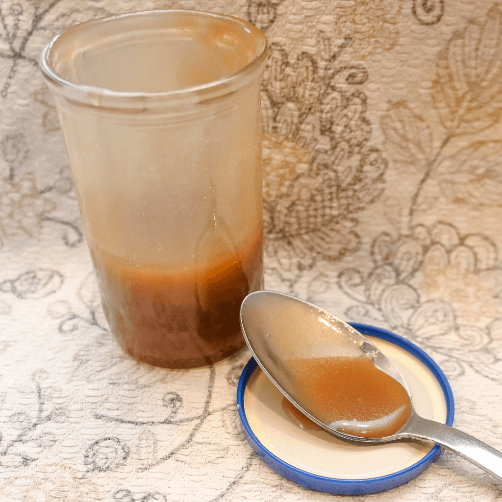 A jar of small batch microwave caramel sauce with a spoon resting on the lid. 